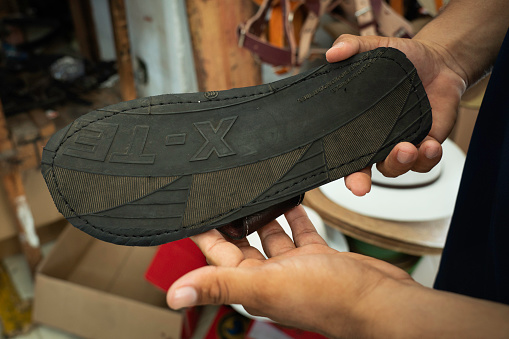 Yucatan, Mexico - April 16, 2021: A Hispanic male shows the bottom of his handmade sandals made from tires at a market in the village of Valladolid