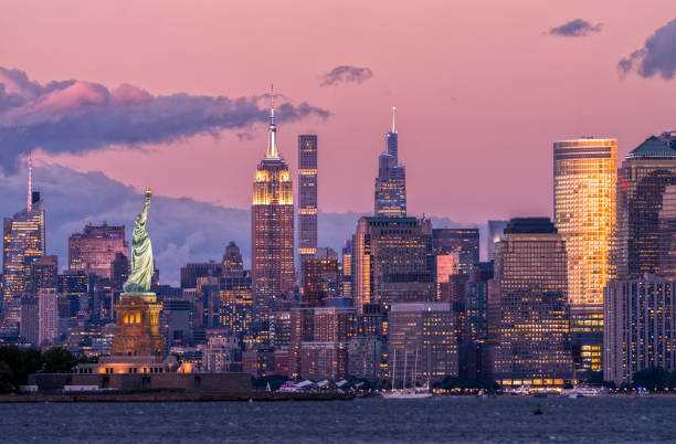 horizonte de la ciudad de nueva york y estatua de la libertad al atardecer - building exterior mid atlantic usa usa night fotografías e imágenes de stock