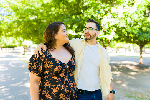 Happy caucasian man dating a plus size beautiful woman and having a date at the park