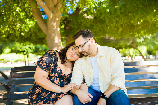 Beautiful loving couple cuddling and hugging on the park bench while relaxing during a date
