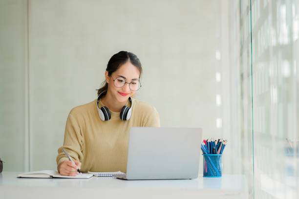 Asian schoolgirl studying and learning online video call using laptop wearing headphones online learning concept Female students attend a webinar on distance learning Asian schoolgirl studying and learning online video call using laptop wearing headphones online learning concept Female students attend a webinar on distance learning online tutors stock pictures, royalty-free photos & images