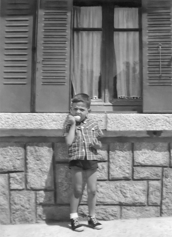 Black and white Image taken in the 60s, little boy having a pear looking at the camera