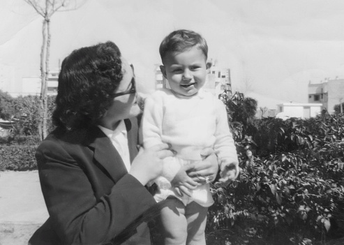 Black and white image taken in the 50s: Smiling woman posing with her son