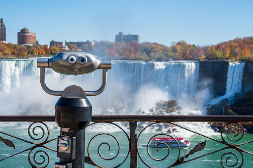 Coin operated binocular viewer telescope. American Falls in autumn foliage season. Niagara Falls City, Ontario, Canada.