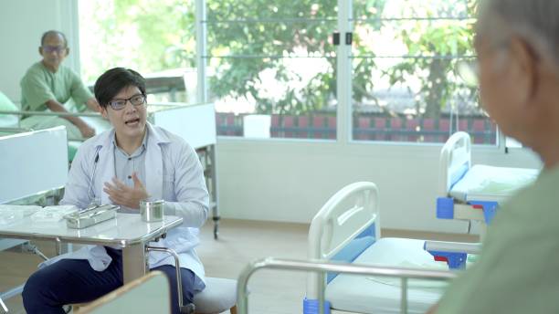 istock Doctor talking to patients in ward. 1439652686