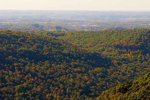 Autumn leaves begin changing in the Cheat River Canyon with the city of Morgantown and West Virginia University in the far distance as seen from the Coopers Rock State Forest overlook.