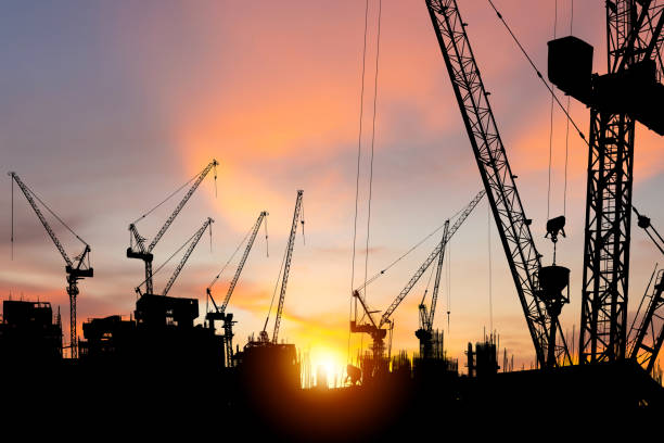 istock Silhouettes of building construction site and construction cranes with sunset background 1439657778