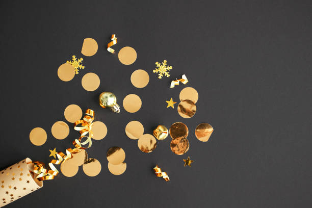 istock Happy New Year! Modern creative firework flat lay. Golden confetti popping from festive wrapping paper on black background. Stylish seasons greeting card. Merry Christmas! Holiday banner 1439668698