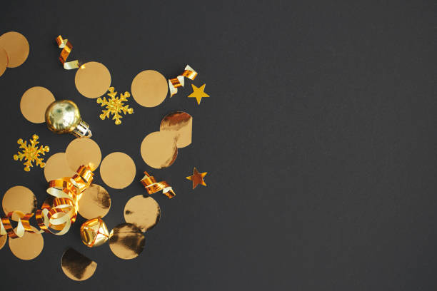 istock Modern christmas flat lay with golden bauble, confetti and decorations on black background. Seasons greeting card template with space for text. Stylish holiday banner. Merry Christmas! 1439669744