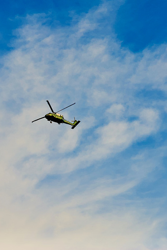 military helicopter in blue sky with clouds