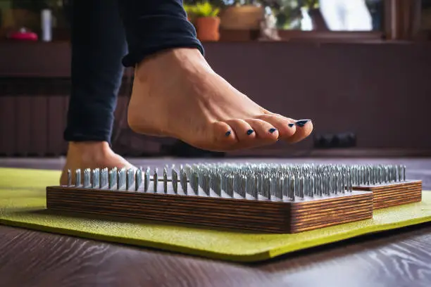 A woman practicing yoga, performs an exercise on a sadhu board with nails, a concept on the topic of a healthy lifestyle and hardening of the body