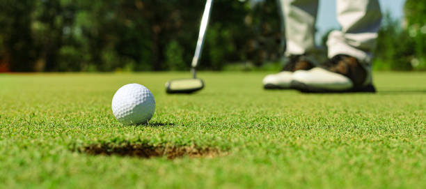 istock Golf player at the putting green hitting ball into a hole. 1439677633