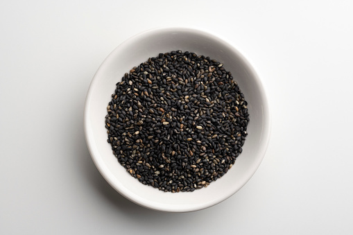 Toasted black sesame seeds on white background.