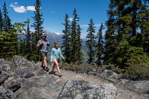 A father and her young daughter enjoy hiking the trails in the Jasper National Park in Canada. Outdoor activities when travelling through Canada in summer.