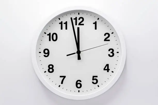 Photo of Simple analog wall clock on white background.