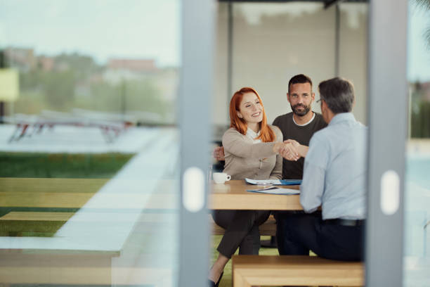 Happy couple came to an agreement with insurance agent in the office. Young happy couple came to a successful agreement with their agent during a meeting in the office. bank manager stock pictures, royalty-free photos & images