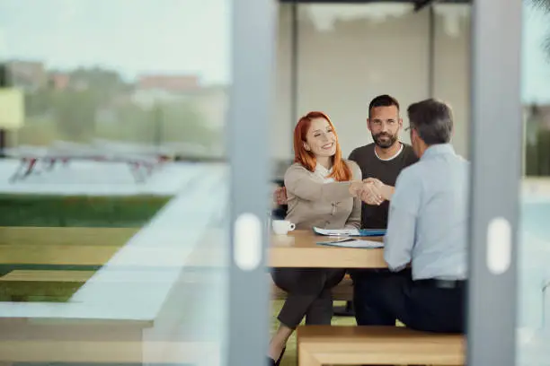 Young happy couple came to a successful agreement with their agent during a meeting in the office.