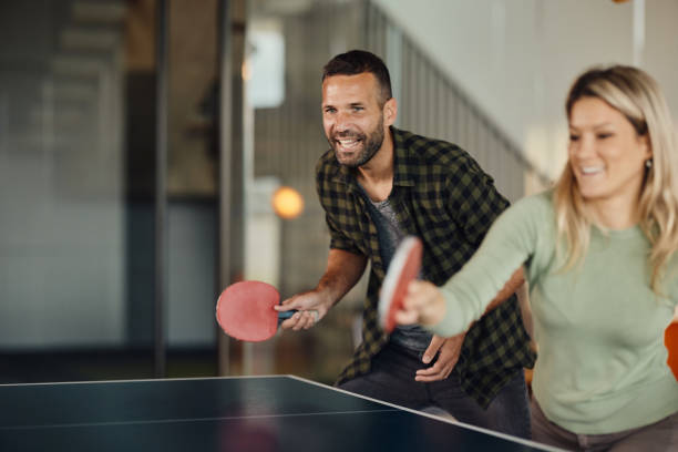 счастливая пара развлекается во время игры в настольный теннис. - table tennis table стоковые фото и изображения