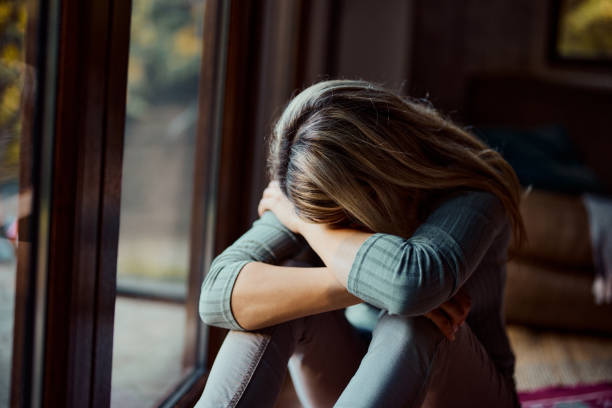 istock Depressed woman crying by the window at home. 1439684598