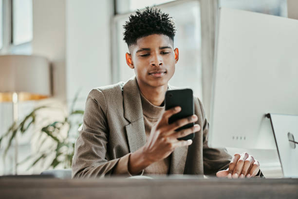 istock Businessman, working and smartphone, communication and technology with computer in office and desk. Young, black man and professional, connect and internet search, text message or social media. 1439688263