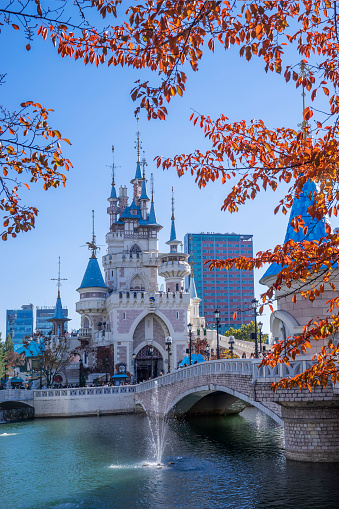 Seoul, South Korea - November 5, 2022: Amber-coloured leaves of cherry trees frame a castle at Lotte World's Magic Island in the middle of Seokchon Lake in Jamsil.