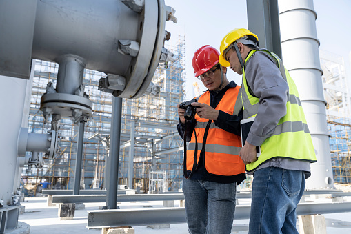 Two male engineers are working at the construction site of the chemical plant under construction