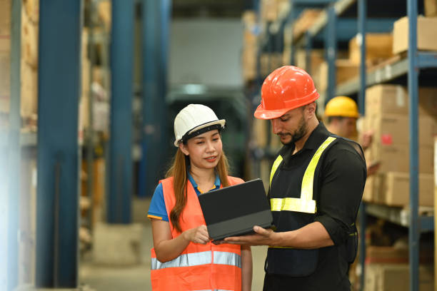 istock Male manager and female workers are checking order details on a tablet while standing between retail warehouse full of shelves. 1439694012