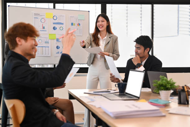 istock Young female manager explaining business plan, presenting new management strategy on flip chart to team at briefing. 1439694041