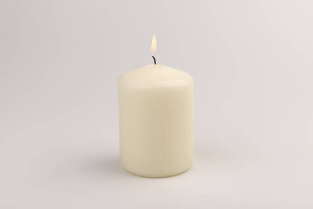 istock Burning white wax candles on white background. 1439694875