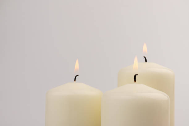 istock Burning white wax candles on white background. 1439694920