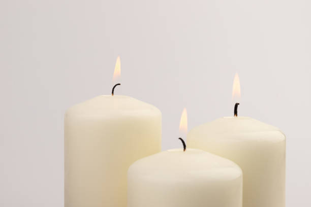 istock Burning white wax candles on white background. 1439694967