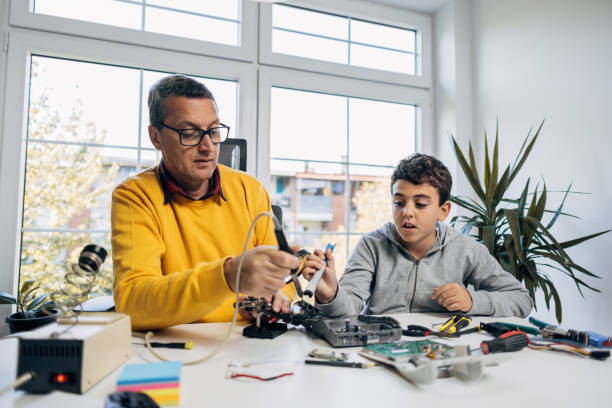 istock Son helping to father while he soldering an components of electrical device 1439695142