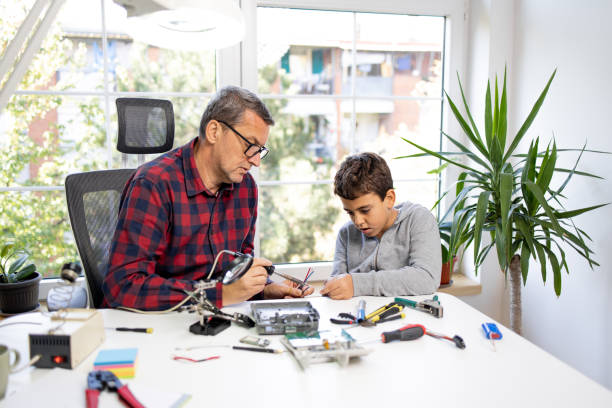 istock Son helping to father while he soldering an components of electrical device 1439695340
