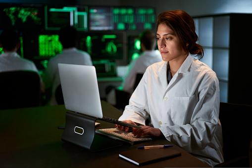 Medical Research Scientist Typing on His Desktop Computer in a Biological Applied Science Research Laboratory. Lab Engineers in White Coats Conduct Experiments Background. High quality 4k footage