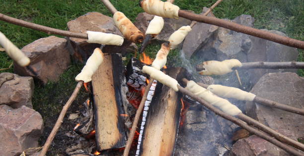 Making stick bread around the campfire stock photo