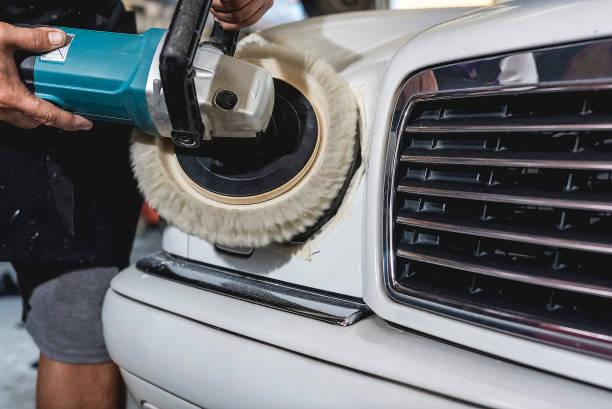 A man polishing the headlights of a white sedan with an electric buffing machine. Restoring foggy headlights at an auto detailing shop. A man polishing the headlights of a white sedan with an electric buffing machine. Restoring foggy headlights at an auto detailing shop. car Power Waxer stock pictures, royalty-free photos & images