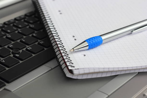 a laptop keyboard with a block and pen