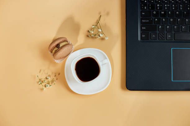 istock Flat lay, top view office table desk, workspace with laptop, macaroon with coffee cup and flowers, on orange background, working from home, distant work. 1439706857