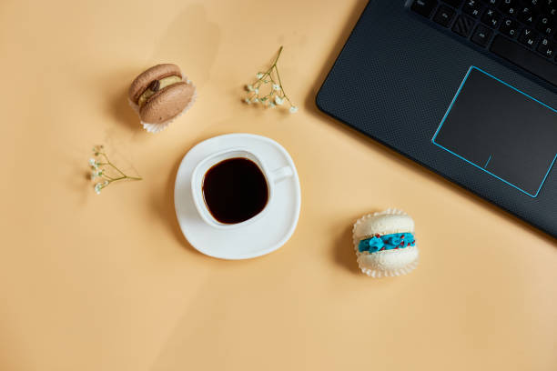 istock Flat lay, top view office table desk, workspace with laptop, macaroon with coffee cup and flowers, on orange background, working from home, distant work. 1439706874