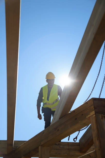 istock Construction worker standing on a wooden house construction site 1439709153