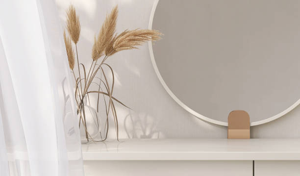 istock Minimal, modern and contemporary design of creamed colored dressing table with round vanity mirror, vase of pampas in dappled sunlight from window curtain in white wall bedroom 1439710331
