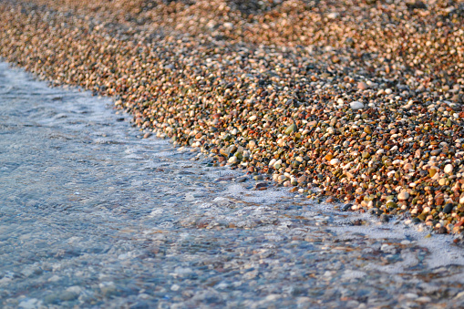 Small pebbles and the sea on the turkish beach.  Beautiful  texture of small stones and sea wave. Background