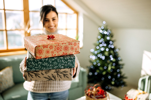 Young beautiful woman holding wrapped gifts in her apartment