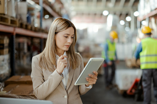 Female warehouse manager holding a digital tablet checks the amount of goods in the warehouse
