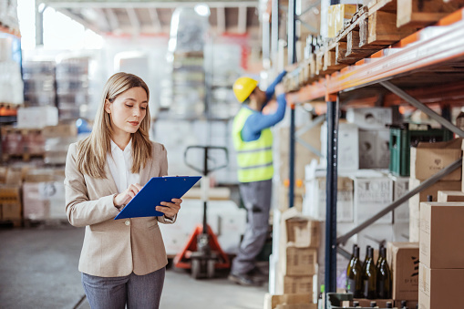 Female warehouse manager holding a clipboard while doing inventory