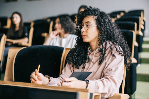 giovane donna che ascolta la lezione universitaria - aula universitaria foto e immagini stock