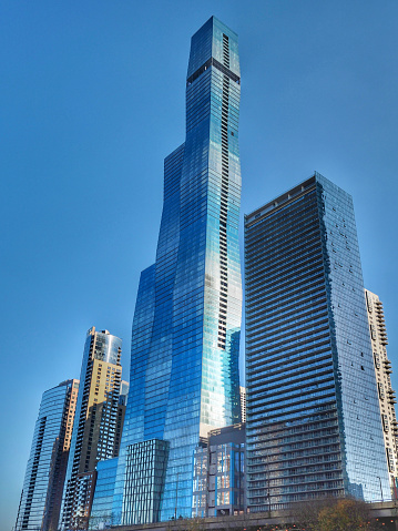 Modern urban skyscrapers in downtown Chicago from below to the blue summer sky. Sun reflecting in the glass facades of the urban futuristic buildings. Chicago, Illinois, USA