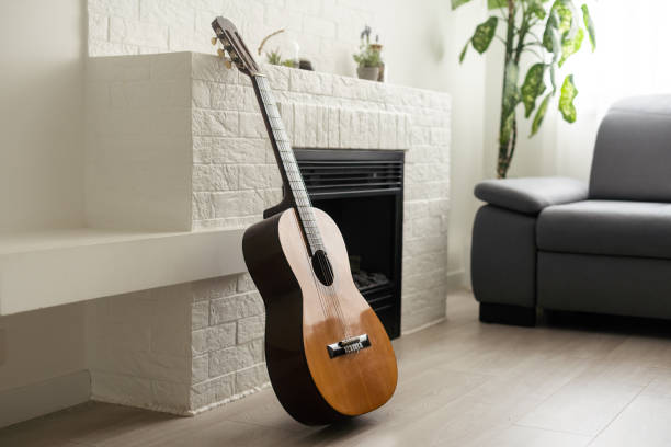 Minimalistic interior design concept. Acoustic guitar on grey textile sofa in spacious room of loft style apartment with wood textured laminated flooring. Background, copy space, close up.