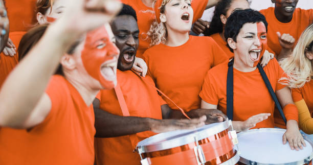 фанаты многорасового оранжевого спорта кричат, поддерживая свою команду - футбольные болельщики веселятся на соревнованиях - сосредоточьт - fan dutch flag women colors стоковые фото и изображения