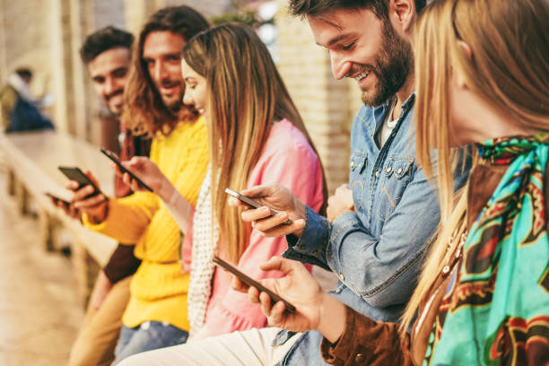 Group of friends using mobile phones outdoors - Focus on right man face stock photo